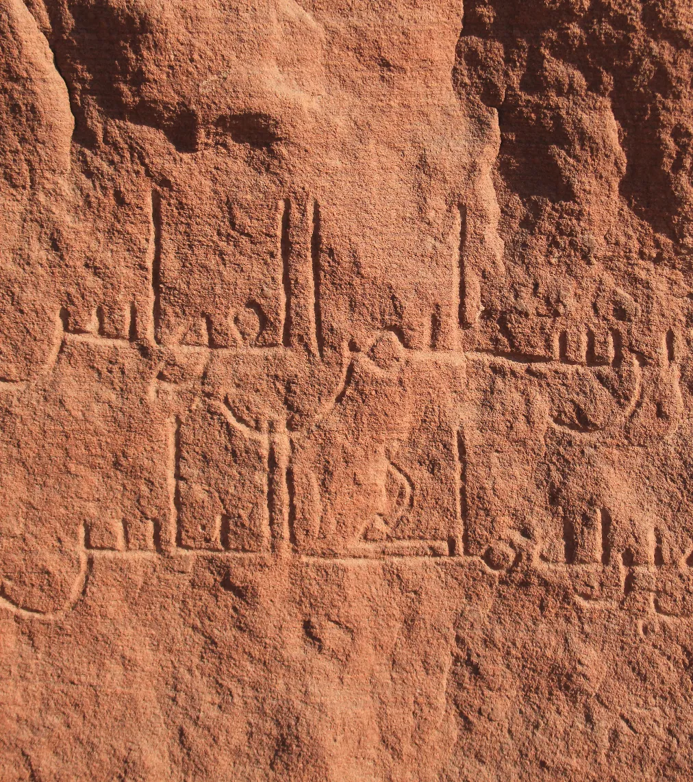 A sandstone surface carved with several lines of early Arabic inscription.