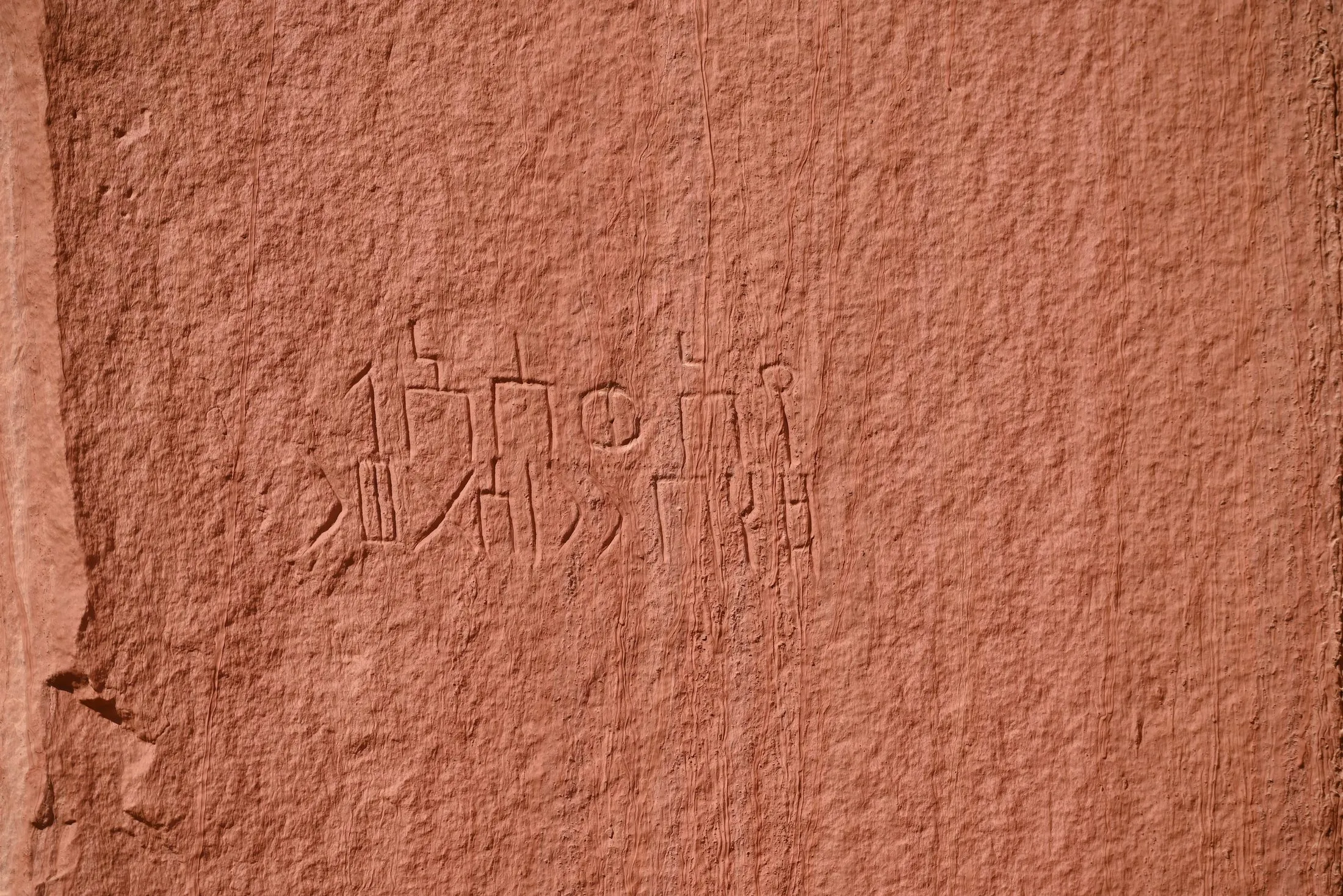 A red sandstone rock face incised with two lines of Minaic inscription.